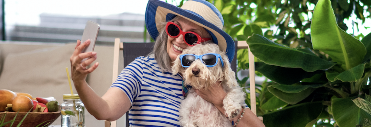 Woman and her dog wear sunglasses while taking a phone selfie