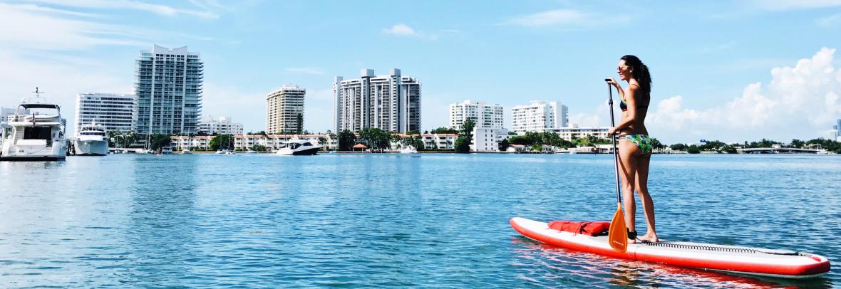 woman paddleboarding with florida skyline in background