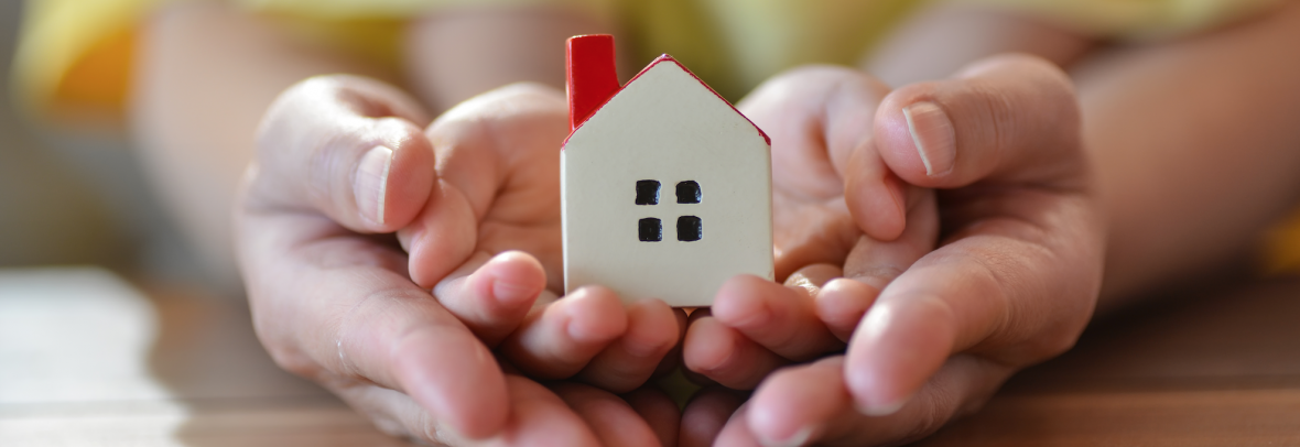 And adult and child's hands holding tiny house