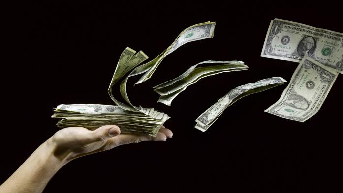 Money blows up and away from an open hand