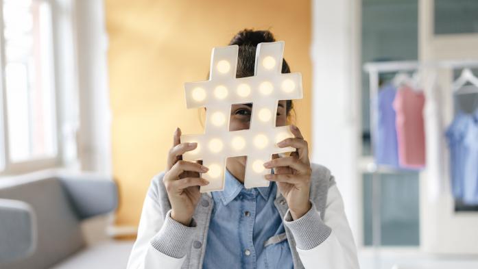 Woman hiding behind big hashtag