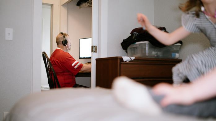 Many with headphones working inside a closet as a young child plays nearby