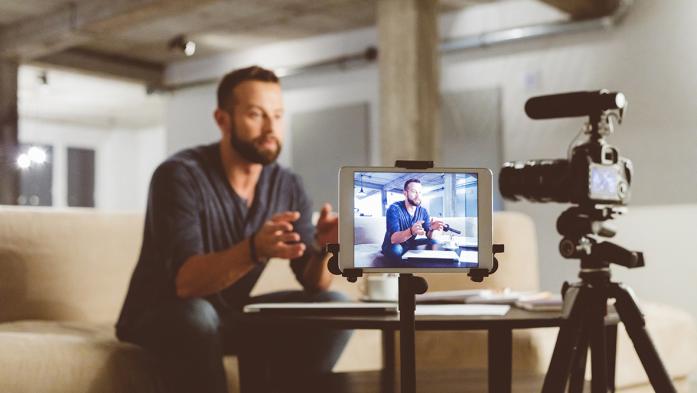 Photo of a man recording a video of himself in his office