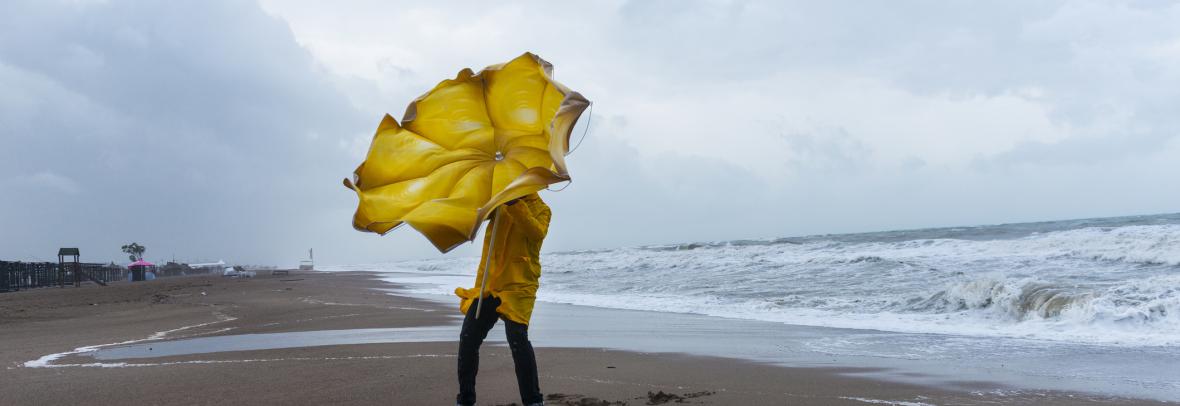 Man with umbrella on beach during storm