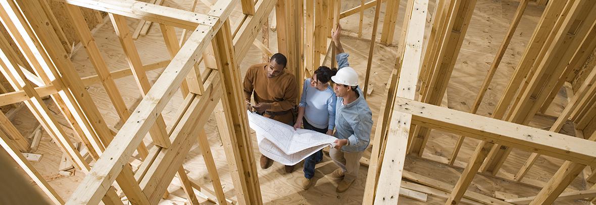 photo from above of a couple looking at blueprints in a new home