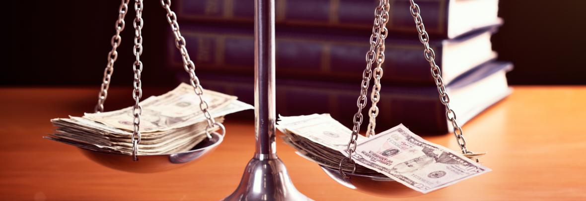 Model scales of justice are weighted with banknotes. The scale are weighed down with banknotes.