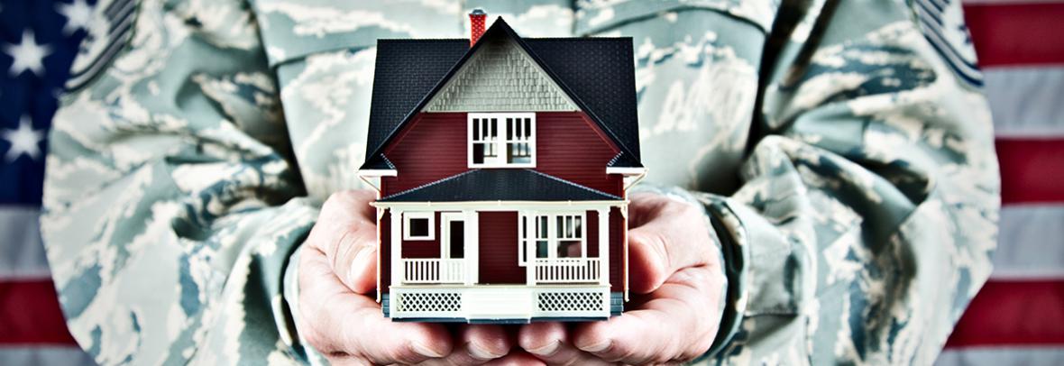 soldier in camo holding a house in his hands