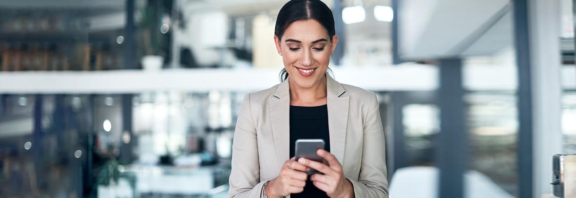 Business woman smiling while looking at her smartphone