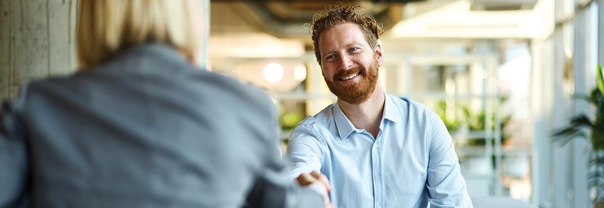 Business man reaching to shake the hand of another colleague