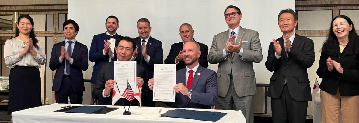 Florida Realtors Pres. Tim Weisheyer, left, with JARECO Chair Masayuki Nakagawa, right, show the signed agreement between the Florida and Japan regional real estate groups while others look on.