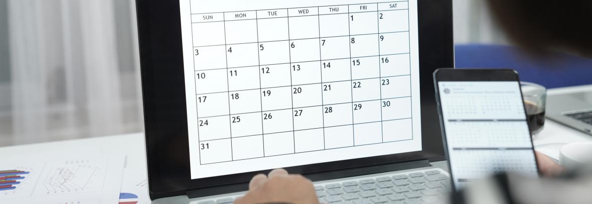 Women work from home using laptop to check time table while reading calendar on mobile phone in hand as well