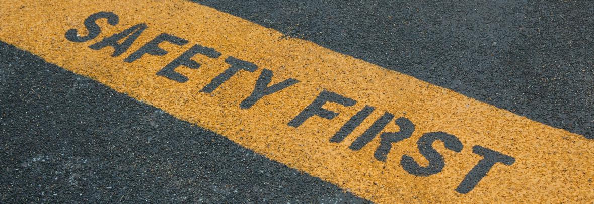 image of road asphalt with yellow line across it saying safety first