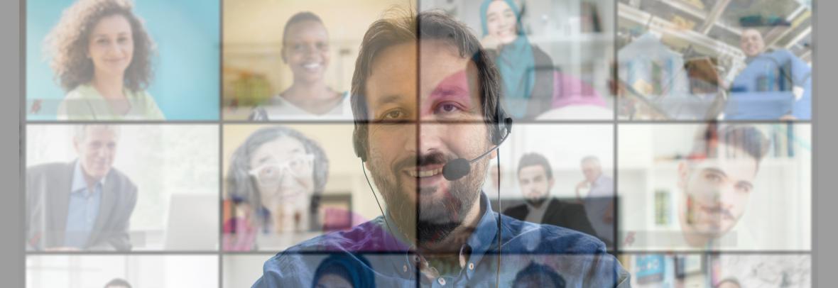 Man at computer overshadowed by other people attending an online class