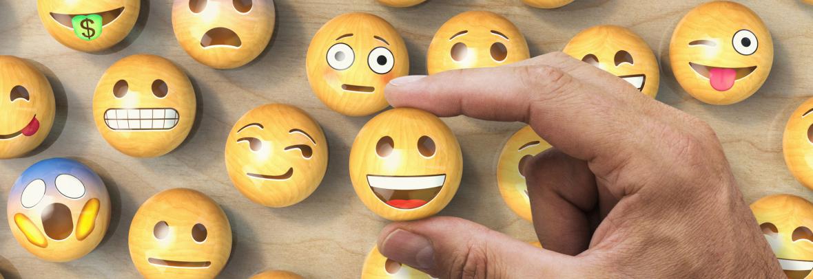 Man's hand picking an emoji among different expressions
