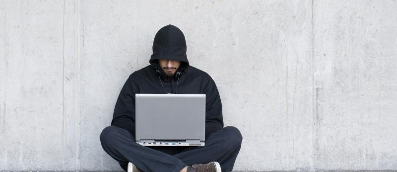 man in hood using computer