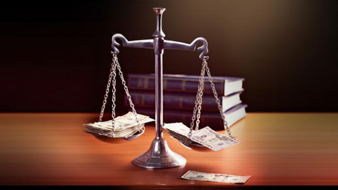 Model scales of justice are weighted with banknotes. The scale are weighed down with banknotes.