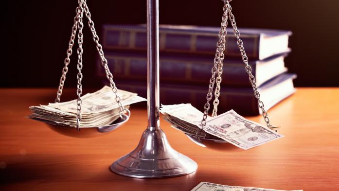 Model scales of justice are weighted with banknotes. The scale are weighed down with banknotes.