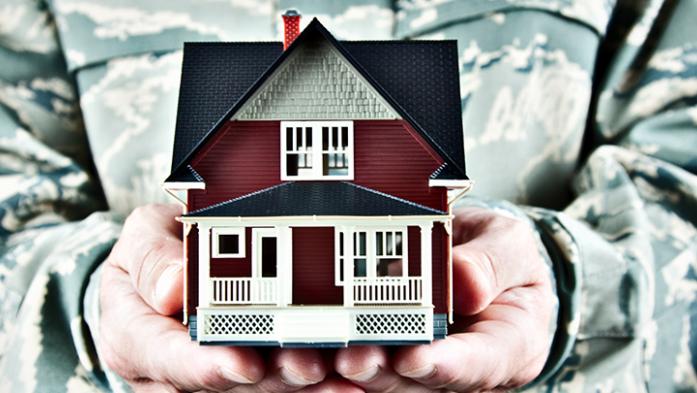 soldier in camo holding a house in his hands