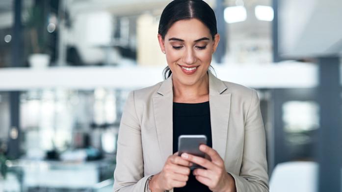 Business woman smiling while looking at her smartphone