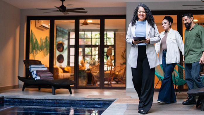 Photo of realtor showing couple a luxury home and pool deck