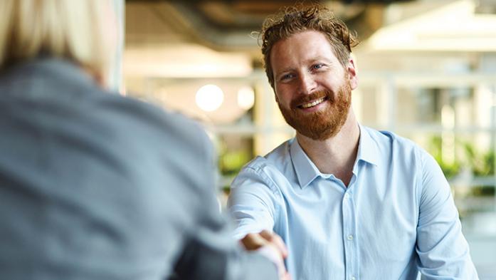 Business man reaching to shake the hand of another colleague