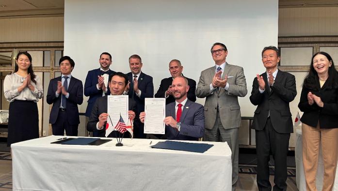 Florida Realtors Pres. Tim Weisheyer, left, with JARECO Chair Masayuki Nakagawa, right, show the signed agreement between the Florida and Japan regional real estate groups while others look on.